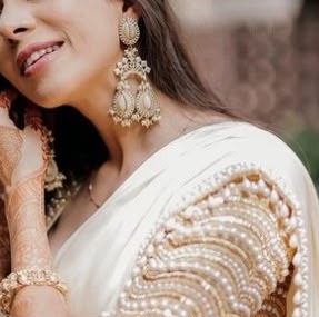 Close-up of a smile, pearl chandbali earrings and the sculpted pearl blouse sleeve