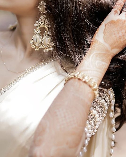 A pearl chandbali earring, mehndi and a pearl-edged sleeve