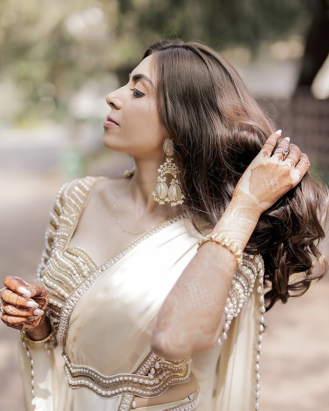 Simran in an ivory satin saree with a sculpted pearl-and-gold blouse, touching her hair