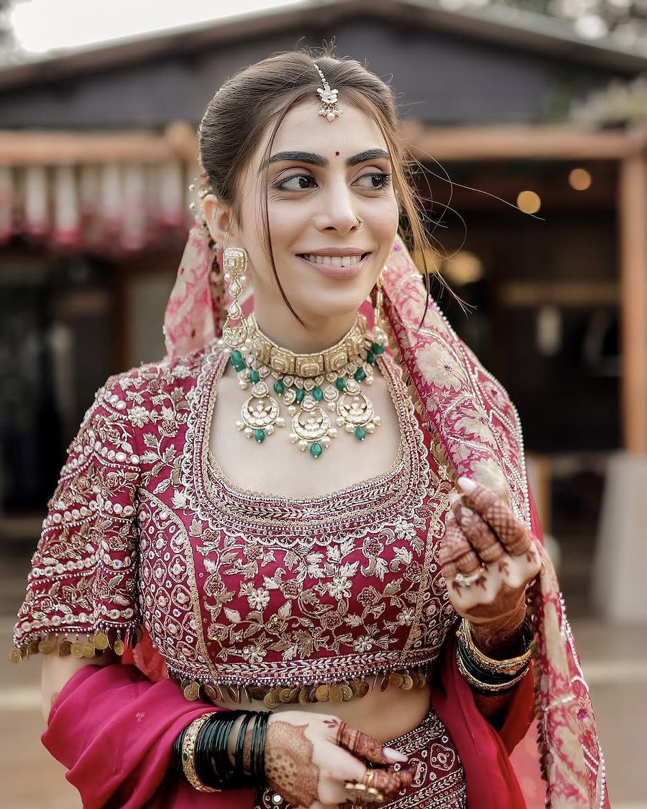 Simran in a rani-pink embroidered lehenga with a kundan and emerald necklace