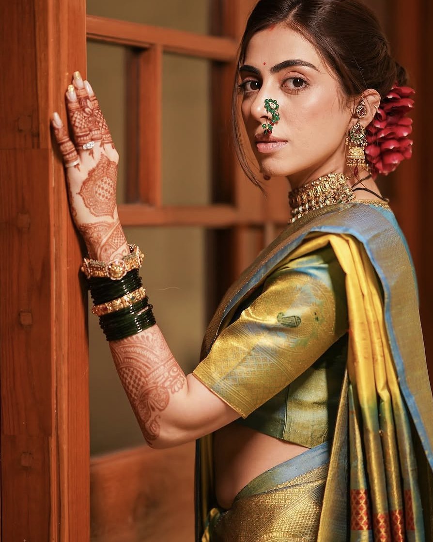 Simran in a Paithani with a nath, gajra and green glass bangles, by a carved wooden door