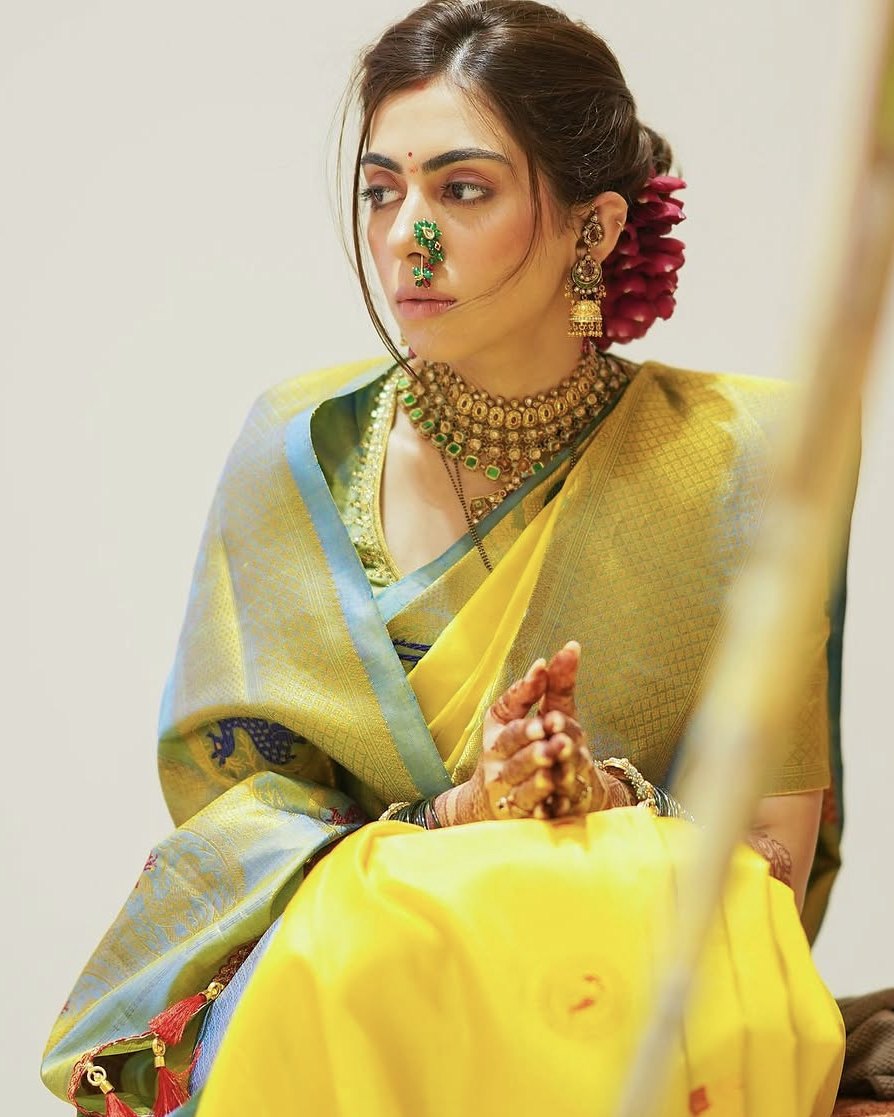 Simran seated in a yellow Paithani with a peacock-blue border, hands folded